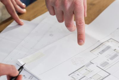 Two people discussing architectural blueprints with one pointing and the other holding a pen.