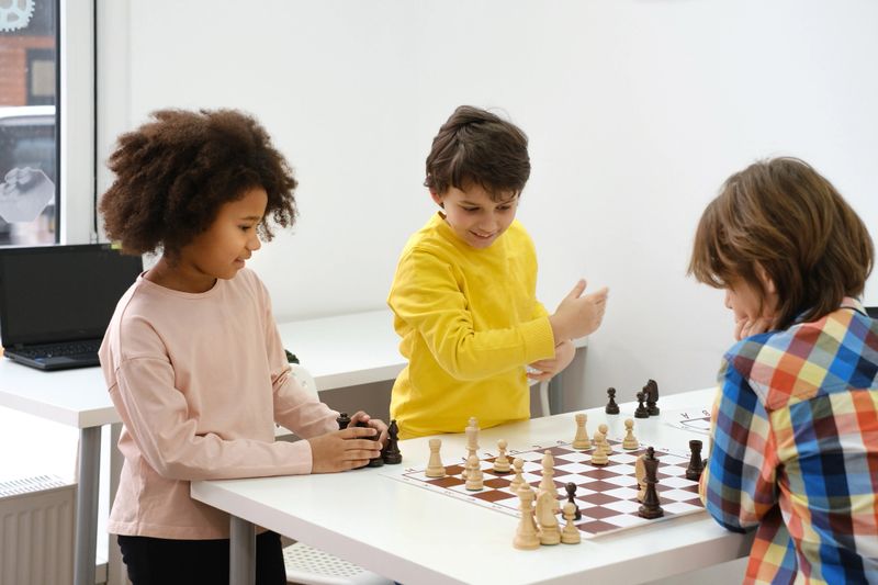 Diverse Group of kids playing chess. Concentrated multiethnic clever children with board game having fun at school. African American girl and Caucasian boys on chess lesson strategy