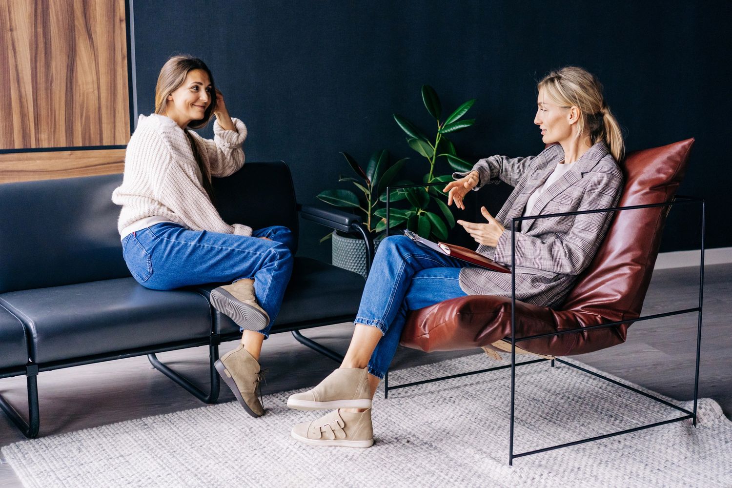 Two women engaged in a friendly conversation in a modern office setting.