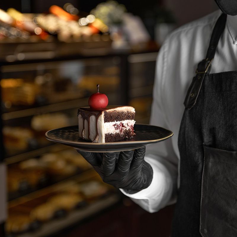 Layered chocolate cake with mascarpone cream, decorated with sour cherries. The waiter holds a plate with dessert in his hand