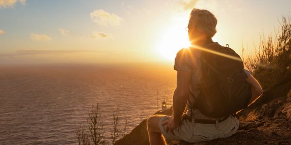 Person watches sunset by the ocean.