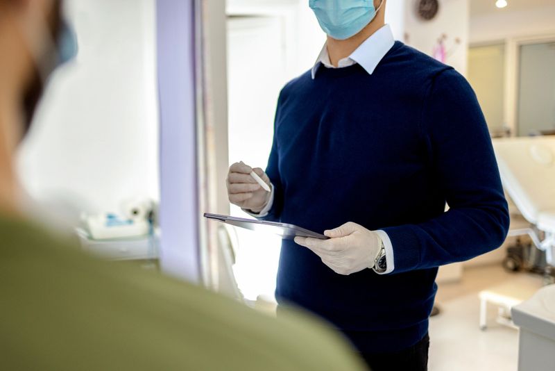 Anonymous doctor in his office holding a tablet and explaining the issue to the unrecognizable patient.