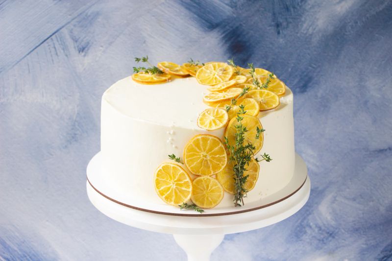White cake on stand decorated dried lemon slices and thyme. Lemon cake, recipe menu template