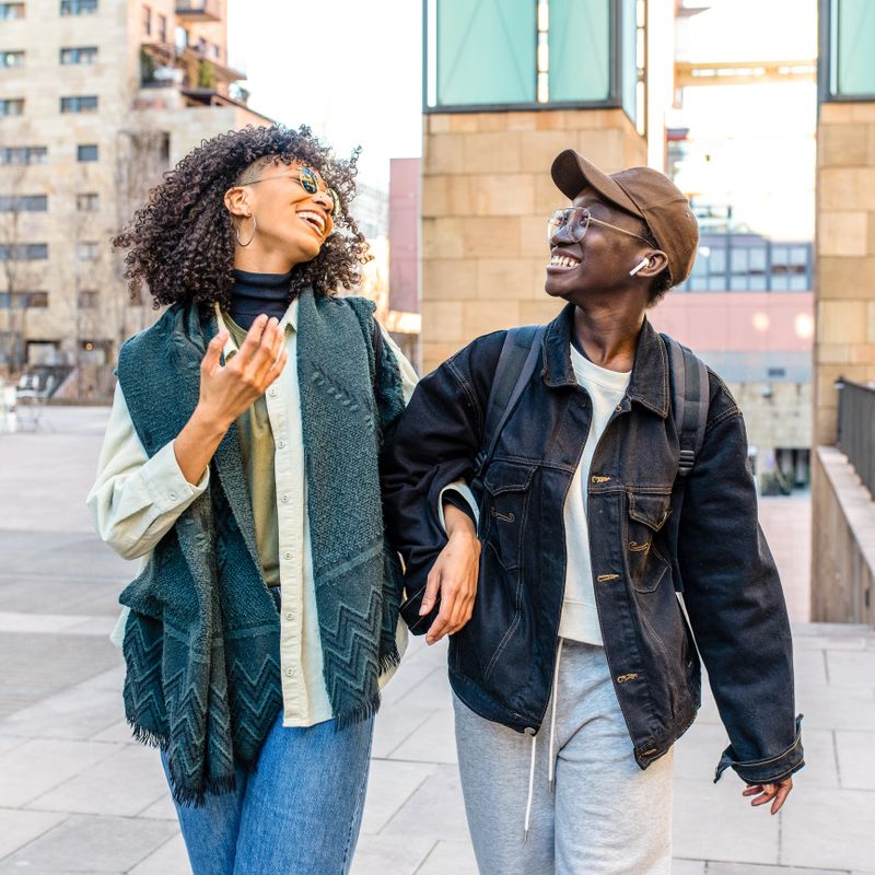two young African American women walking in urban scenery, female best friends chatting and laughing, fashion stret style people, generation z girls