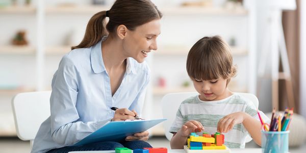 Specialist taking notes while a young boy plays with toys