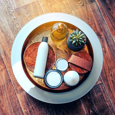 A stylish tray with skincare items and a small succulent plant on wooden flooring.