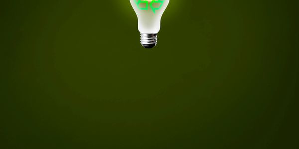 Light bulb with a glowing recycling symbol on a green background.