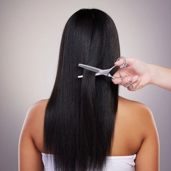 Person with long black hair getting a haircut with scissors and comb.