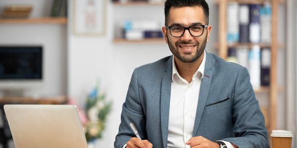 Smiling businessman working at his desk with laptop and documents.