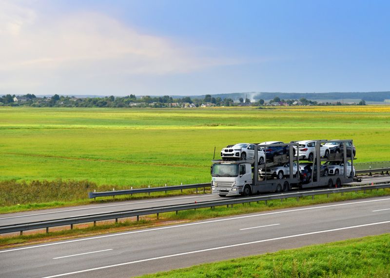 Car carrier trailer transports cars on highway. Auto transport and car shipping services concept. Truck with Semi-remorque. Cars Shipping and transporter.