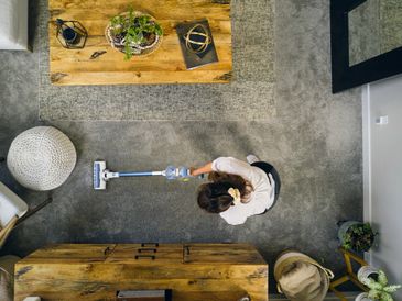 Overhead view of a woman vacuuming a cozy living room with a cordless vacuum.