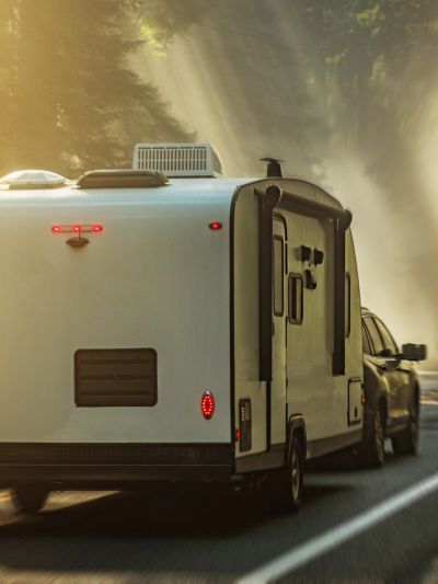 RV trailer being towed down a road in morning light.