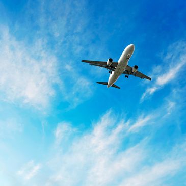 Commercial airplane flying in a partly cloudy blue sky.