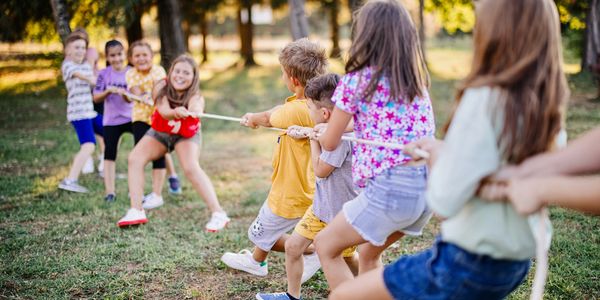 Children smiling outdoors on a sunny day.