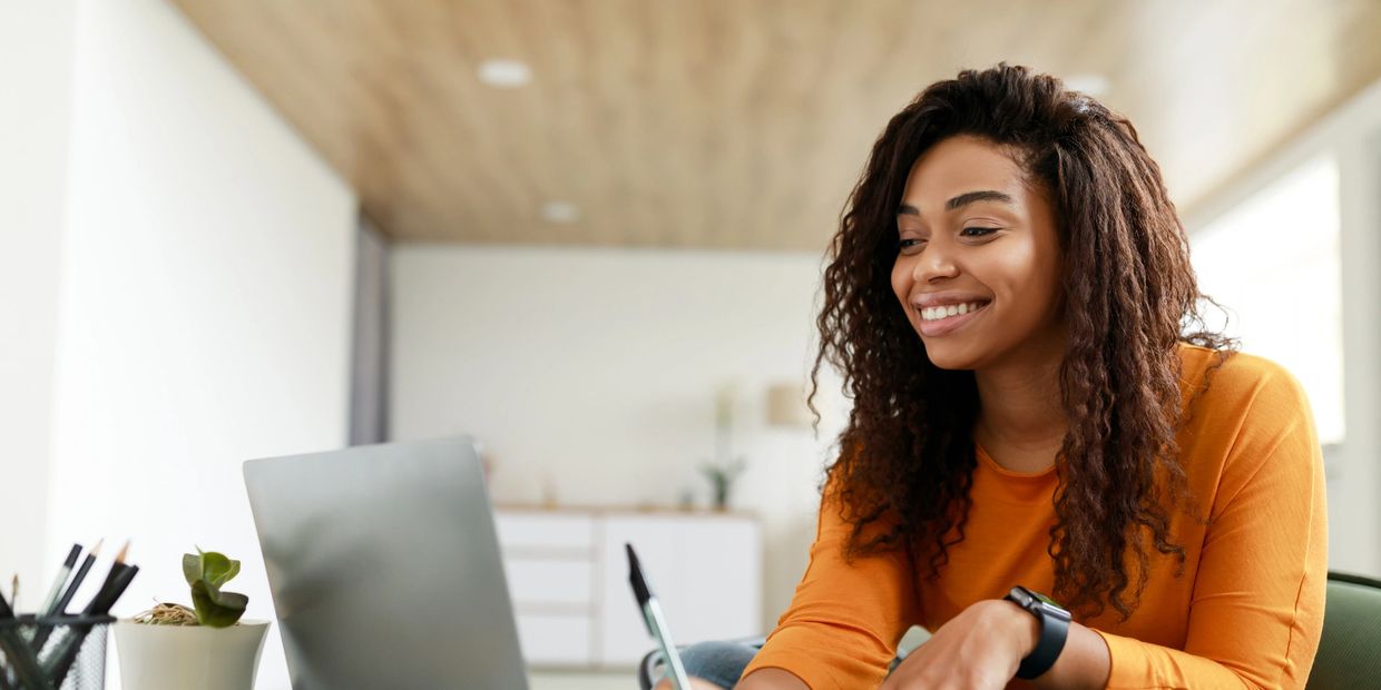 Smiling woman using laptop at home.