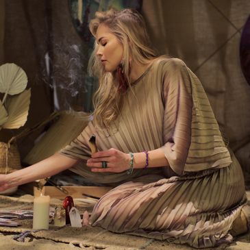 Woman lighting a candle in a serene, dimly lit space.