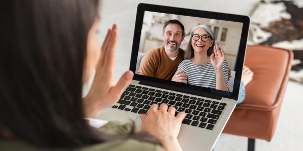 Person video calling happy couple on laptop.