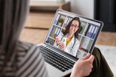 Woman video chatting with a doctor on a laptop.