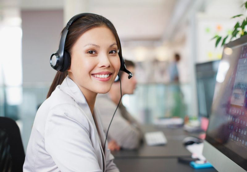 Portrait of smiling businesswoman with headset at computer in office
