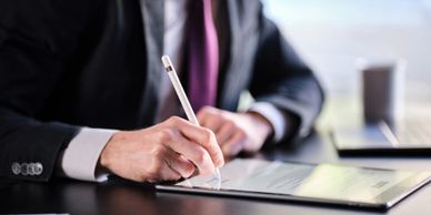 A person in business attire signing a digital document with a stylus.