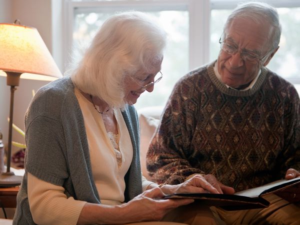 Elderly couple happily looking through a photo album together.