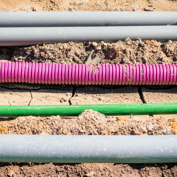 Colorful utility pipes laid in trenches on a construction site.