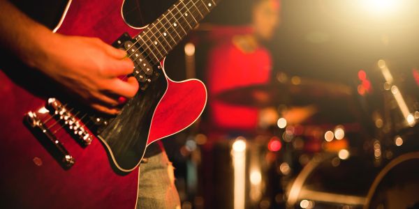 Close-up of a musician playing a red electric guitar during a live performance.