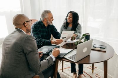 Couple discussing documents with a financial advisor in a bright office.