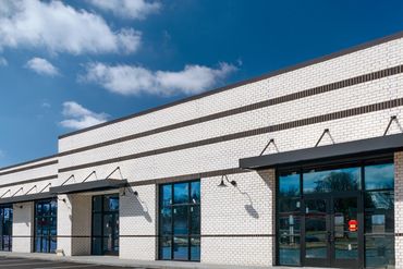 Newly constructed empty retail strip center with parking spaces under a clear sky.