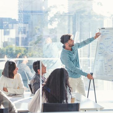 Man presenting business strategy on whiteboard to attentive team in modern office.
