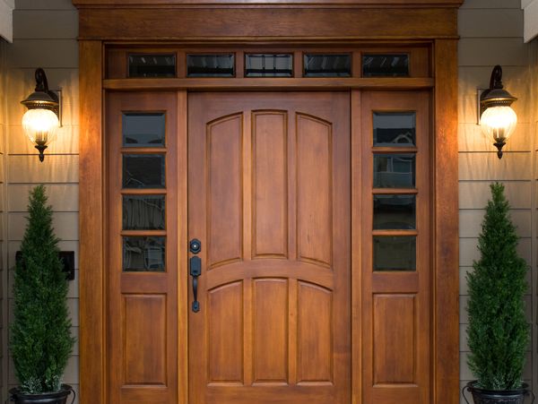 Elegant wooden front door with sidelights and outdoor lanterns.