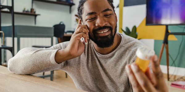 Man talking on phone while holding medicine bottle.