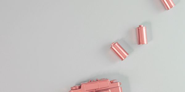 Pink toy camera with scattered film rolls on a gray surface.