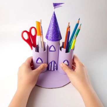 Purple castle-shaped organizer holding stationery items like scissors and colored pencils.