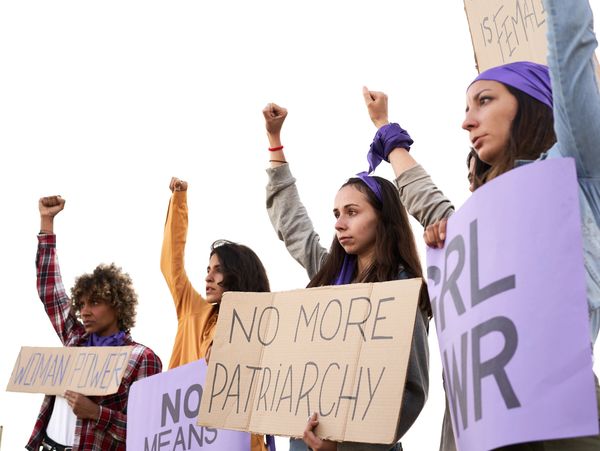 Women protesting with signs against patriarchy and for female empowerment.