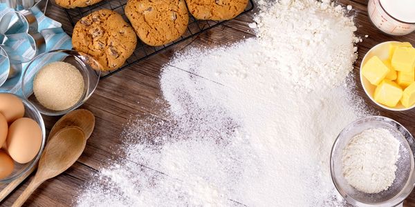 Freshly baked cookies with baking ingredients on a wooden table.