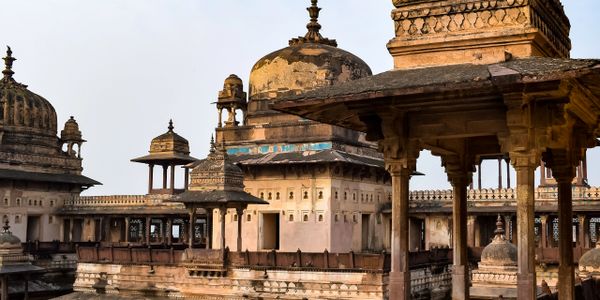 Historic Indian palace with intricate domes and arches under clear sky.