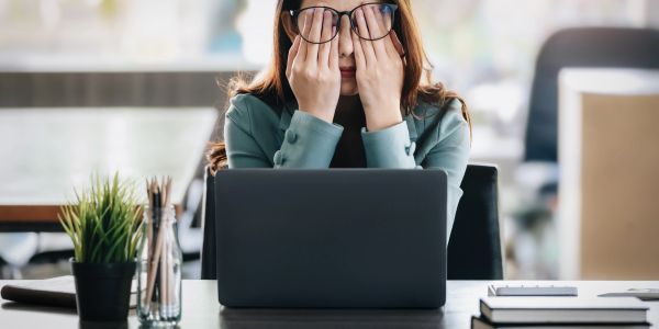 Woman rubbing her eyes at work with a laptop.