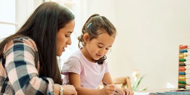 Woman helping young girl with homework.