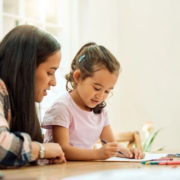 Mother helping daughter with homework at the table.