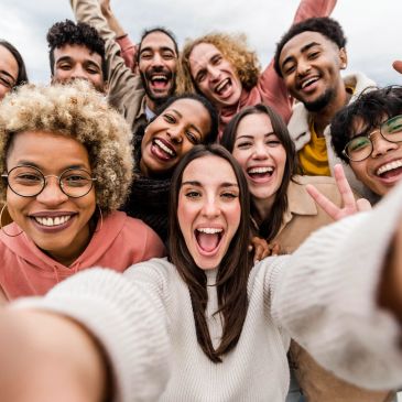 Group of diverse friends taking a cheerful selfie outdoors.
