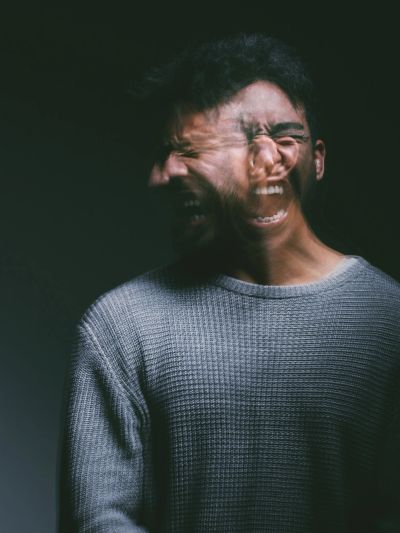 A man with a blurred double exposure showing intense emotions of anger and anguish.