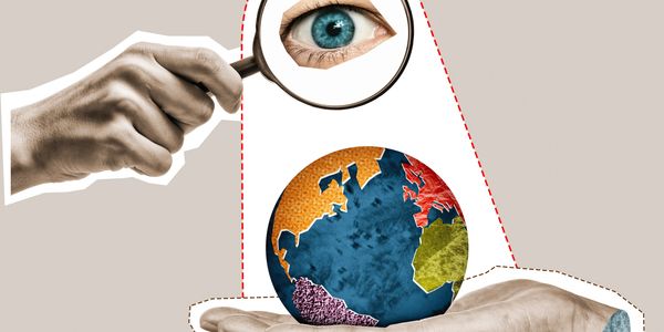A magnifying glass reveals a detailed eye over a colorful globe held by a hand.