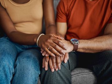 Couple holding hands, showing connection and support.