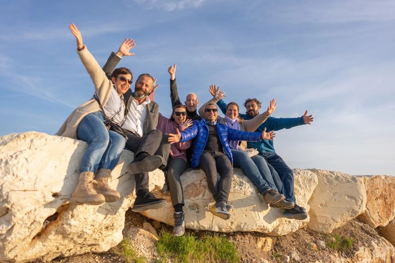 Large group of friends having fun sitting on rock in nature.