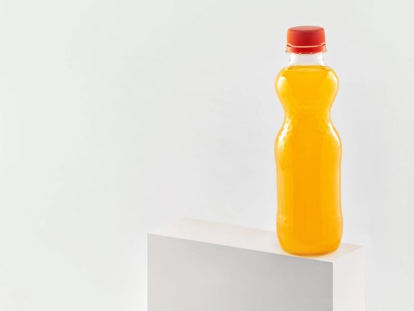 Bottle of orange juice with a red cap.