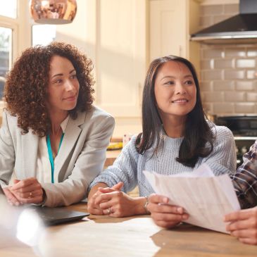 Women discussing documents at a kitchen table.