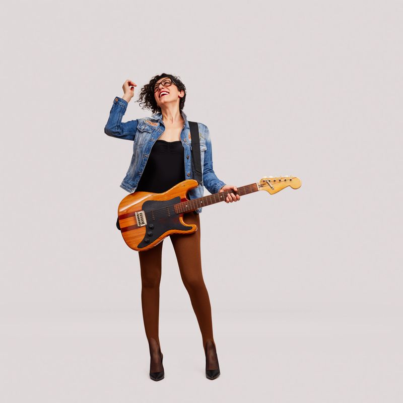 Cheerful female rock musician enjoys the music with electric guitar on white background