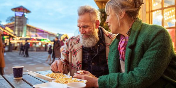 Older couple enjoying fries at an outdoor fair.