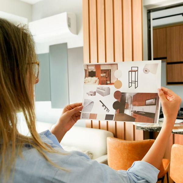 Person holding an interior design mood board with furniture and color samples.